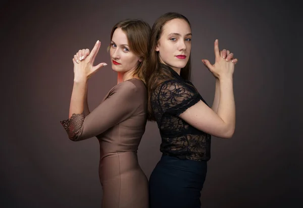 Immagine di due amiche donne in piedi schiena contro schiena su sfondo grigio — Foto Stock