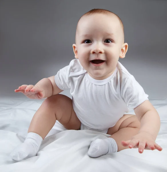 Foto de um bebê sorridente de dez meses olhando para a frente em um fundo branco — Fotografia de Stock