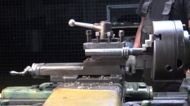 Torna tezgahında metal detaylarıyla çalışan bir adamın görüntüsü.