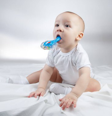 Ağzı mavi çıngıraklı on aylık bir bebeğin resmi.