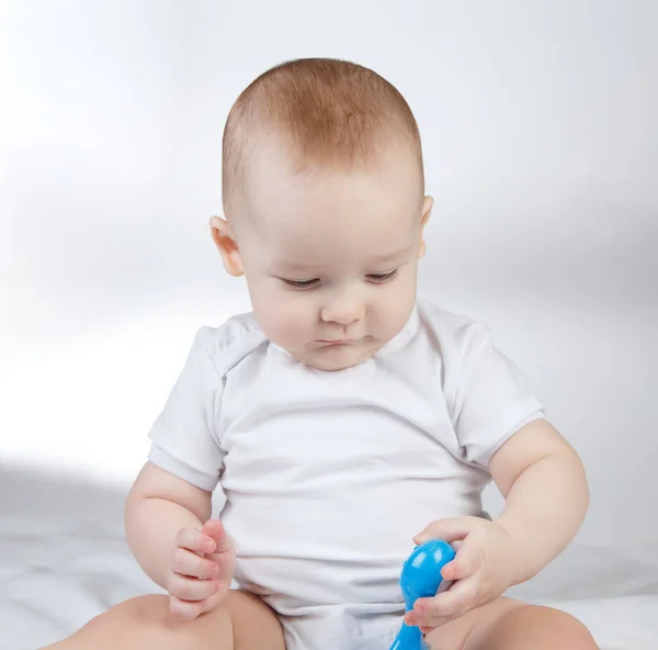 Photo of a ten-month-old baby boy looking at blue rattle — Stock Photo, Image