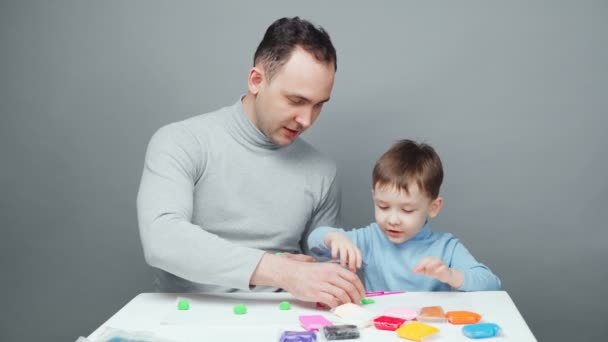 Beelden van vader en zoon beeldhouwen in plasticine op grijze achtergrond — Stockvideo