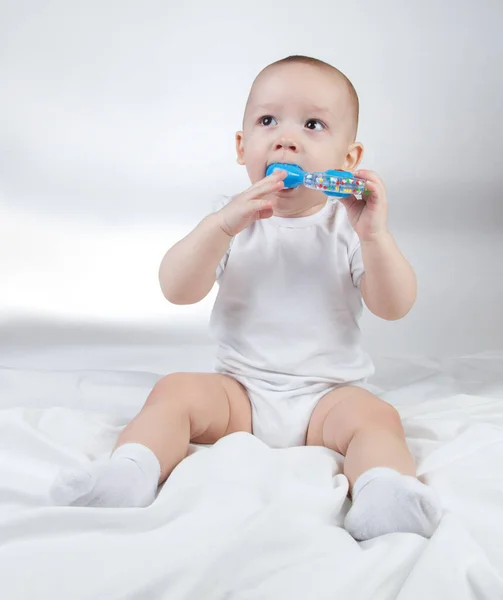 Image of a ten-month-old child with blue rattle in mouth — Stock Photo, Image