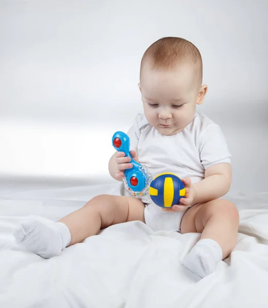 Foto de un bebé de diez meses que elige entre sonajero y pelota —  Fotos de Stock