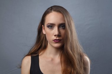 Gri arkaplanda parlak makyajlı genç bir kadın resmi