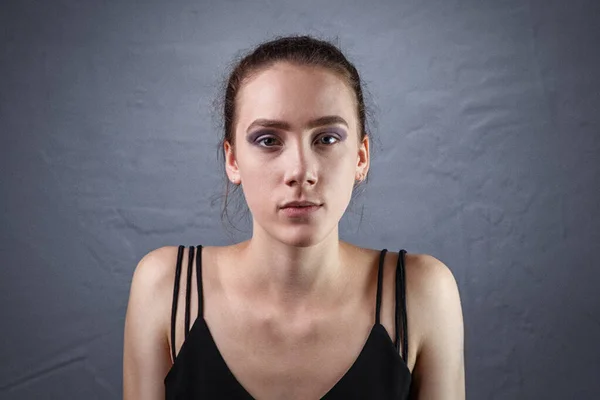 Portrait de jeune femme avec un maquillage inachevé sur fond gris — Photo