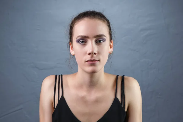 Prise de vue de jeune femme avec un maquillage inachevé sur fond gris — Photo