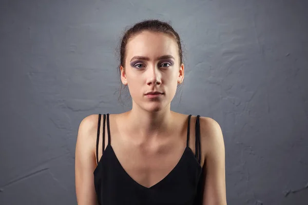 Молодая женщина с незаконченным макияжем на сером фоне — стоковое фото
