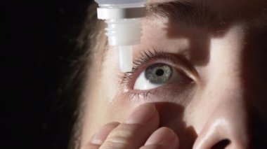 Göz damlası kullanan genç bir kadının yakın plan çekimi.