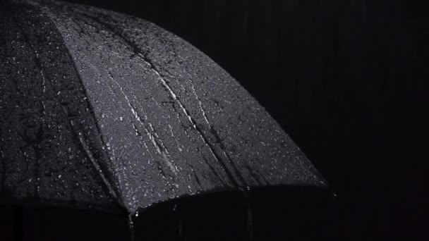 Verfilmung von schwarzem Regenschirm und Regentropfen auf schwarzem Hintergrund — Stockvideo