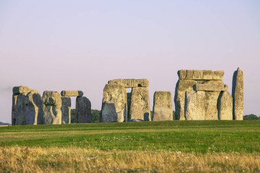 Wiltshire, İngiltere'de Stonehenge ünlü ayakta taşlar. Güneş ışığı, berrak gökyüzü, yeşil çimenler, insan yok.