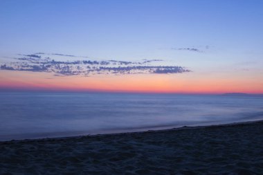 Alacakaranlık turuncu gökyüzü ile uzun deniz manzarası. Canlı gün batımı gökyüzü ve hareket bulanık su manzarası. Marina di Torre del Lago Puccini, İtalya. 