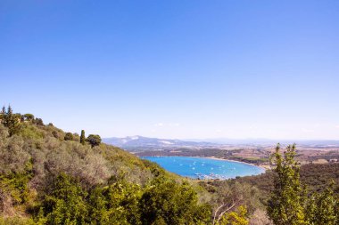 Populonia köyünden Piombino yarımadasındaki Golfo di Baratti koyuna bakın. Denizin turkuvaz suyu, tekneli marina, yazın İtalyan kostüm manzarası..