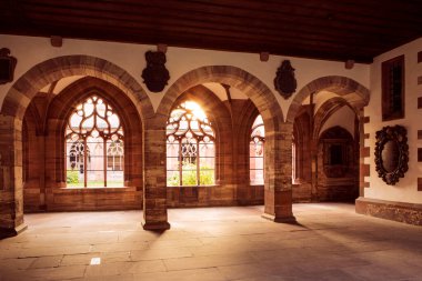 İç manastırda güneş ışığı, kemerli kolonlar ve açık pencereli. İsviçre, Basel 'deki Katedral.
