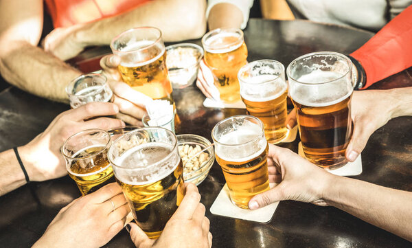 Друзья пьют пиво в ресторане пивоварни - Концепция дружбы с молодыми людьми, наслаждающимися временем вместе и весело проводящими время в крутом винтажном баре - Сосредоточьтесь на среднем правом маленьком стакане
