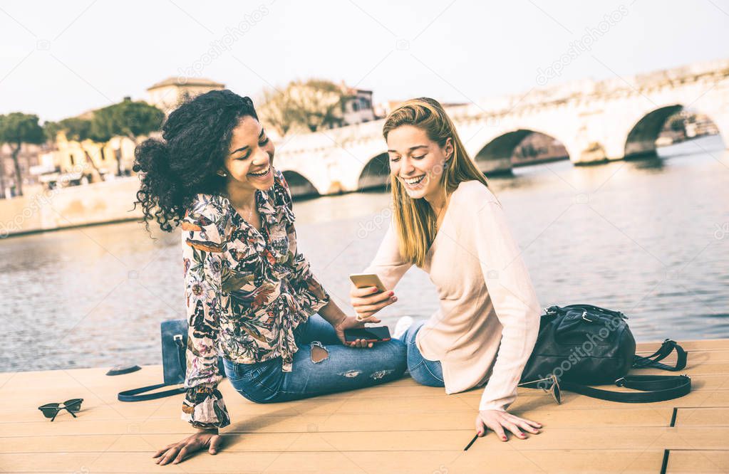 Happy multiracial girlfriends having fun with mobile smart phone at park - Friendship concept with girls at wandering travel - Modern female lifestyle with women best friends - Vintage contrast filter