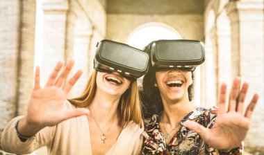 Girlfriends playing on vr glasses outdoors - Virtual reality and wearable tech concept with young people having fun together with headset goggles - Generation z digital trends - Retro contrast filter clipart