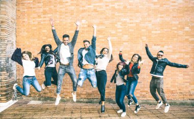 Happy friends millennials jumping and cheering against brick wall in the city - Friendship lifestyle and team concept with young people millenial having fun together - Teal and orange vintage filter clipart
