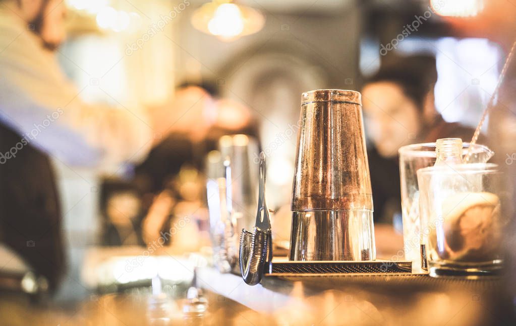 Blurred defocused side view of barman preparing drink to guest at speakeasy cocktail bar - Social gathering concept with people enjoying time together - Warm vintage filter with focus on shaker