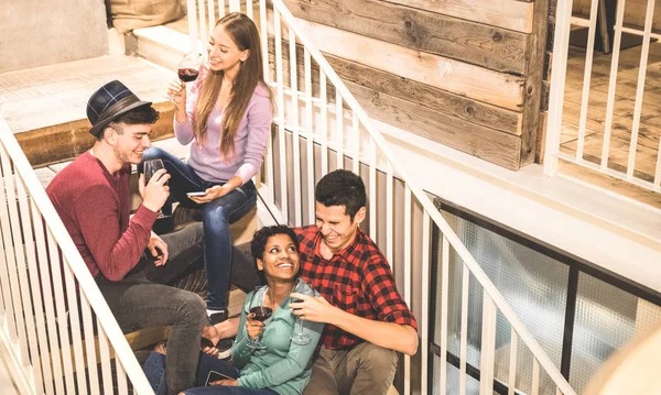 Top side view of multi racial happy friends tasting red wine and having fun at fashion bar winery - Multicultural friendship concept with young people enjoying time on stairs at home drinking together — Stock Photo, Image