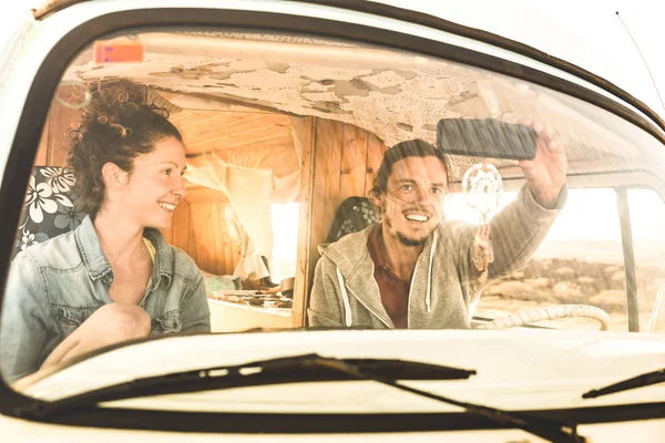 Indie paar klaar voor roadtrip op oldtimer busje vervoer - vakantie levensstijl concept met jonge hippie mensen plezier reizen op minivan avontuur reis - warme heldere filter — Stockfoto