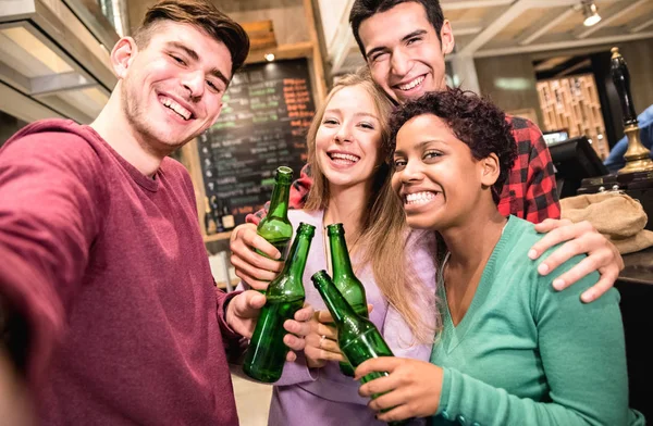 Amigos multirraciales tomando selfie y bebiendo cerveza en el restaurante de la cervecería de lujo - Concepto de amistad con los jóvenes disfrutando del tiempo juntos divirtiéndose en el bar de moda - Centrarse en la chica del medio — Foto de Stock