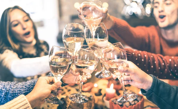 Grupo de amigos comemorando o Natal torrando vinho de champanhe em casa jantar - Conceito de férias de inverno com os jovens desfrutando do tempo e se divertindo juntos - Filtro vintage Azure com foco em óculos — Fotografia de Stock