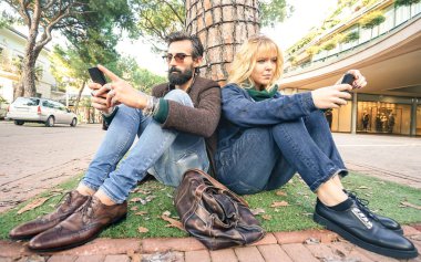 Hipster bin yıllık çift ilgisizlik an smartphone - apati kavramı üzüntü ve mobil akıllı telefon kullanarak yalıtım hakkında - Millenial erkek ve kız arkadaşı ile cep telefonu bağımlılığı