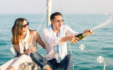 Erkek yüzü güneşli öğleden sonra renk tonları ile yelkenli tekne ile şampanya şarap şişesi - mutlu kız doğum günü partisi cruise seyahat lüks yelkenli üzerinde - tezahürat aşık genç çift odaklanmak