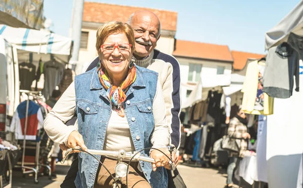 快乐的老夫妇在城市市场上玩自行车 积极好玩的老人概念骑自行车在退休时间 每天的欢乐生活方式没有年龄限制温暖明亮的阳光明媚的天气过滤器 — 图库照片