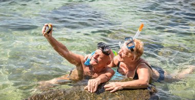 Mutlu emekli çift alarak selfie tropikal deniz gezi su kamera ve şnorkel maskesi - tekne gezisi egzotik senaryolarda snorkeling - yaşlı konsepti ile aktif Büyükler Dünya çapında seyahat ile