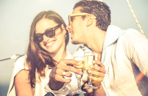Young lovers couple on sailboat with focus on champagne flute glass cheer - Happy exclusive alternative lifestyle concept - Boyfriend whispering girlfriend ear on luxury sailboat - Warm vintage filter — Stock Photo, Image