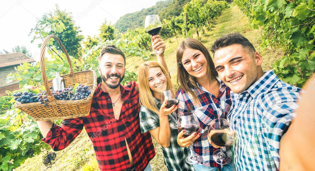 Young friends having fun taking selfie at winery vineyard outdoor - Friendship concept on happy people enjoying harvest together at farm house - Red wine bio production experience - Azure vivid filter
