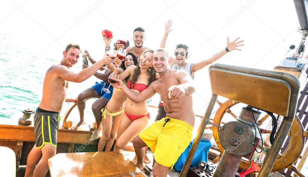 Multiracial millenial friends group having fun cheering at sail boat party - Friendship concept with young multi racial people on luxury sailboat location - Happy travel lifestyle on bright filter