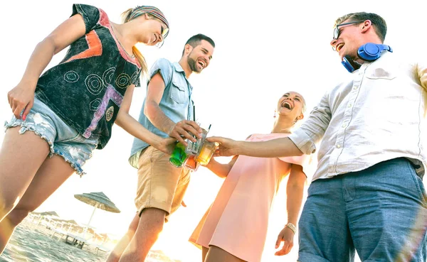 Happy millenial friends group having fun at beach party drinking fancy cocktails at sunset - Summer joy and friendship concept with young people millennials on luxury holiday - Warm sunshine filter — Fotografia de Stock