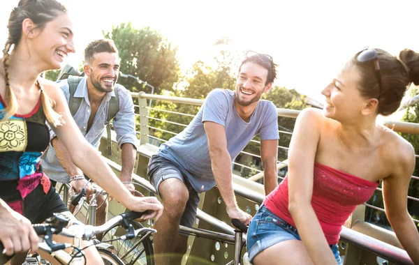 Happy millenial friends having fun riding bicycle in city park - Friendship concept with young millennial people students biking together to university college campus - Bright vivid retro filter — Stock Photo, Image