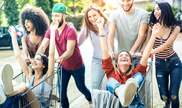 Młodych ludzi wielorasowe zabawy wraz z zakupy koszyka - Millenial znajomych, dzielenie się razem z wózków na parking centrum handlowego - styl życia młodzieży koncepcja koncentrować się na dziewczynę z rąk w górę — Zdjęcie stockowe