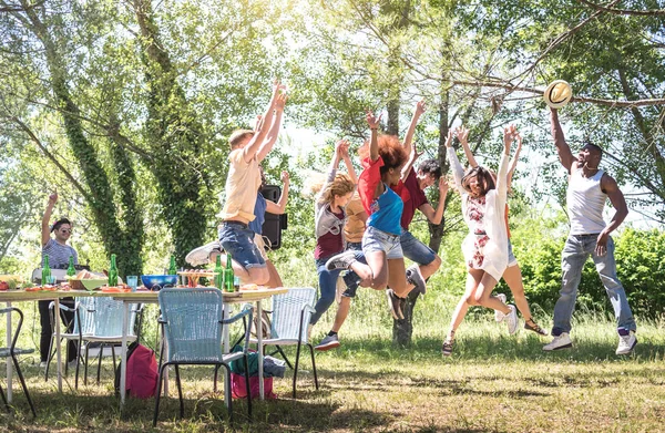 Multiracial friends jumping at barbecue pic nic garden party - Friendship multiccultural concept with young happy people having fun dancing out at spring break camp festiva - Bright warm filter — стоковое фото