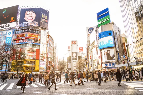 TOKYO - FEBRUARY 28, 2015: everyday life with commuters at rush hour on world famous Shibuya crossroad - International capital city with commercial ads in japanese language on landmark buildings — Stock Photo, Image