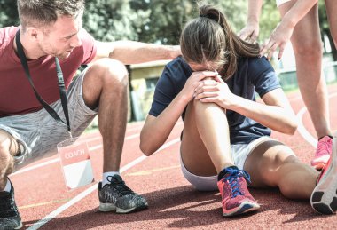 Atletik koşu antrenmanı sırasında yaralanan kadın atlet - Fiziksel kaza sonrası spor öğrencisine bakan erkek antrenör - Genç sportif insanların kazalarla karşı karşıya olduğu takım bakım konsepti
