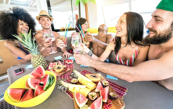 Amis heureux de boire des cocktails de fantaisie au voyage de fête en bateau - Jeunes milléniaux s'amuser en vacances de luxe - Concept de style de vie de voyage avec les milléniaux partageant des boissons à l'apéritif avec des fruits tropicaux — Photo