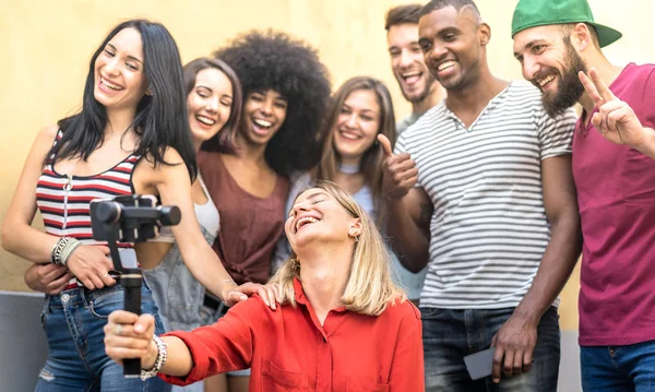 Multiracial young friends taking selfie with mobile smarphone and stabilizer gimbal - Friendship concept with millenial people having fun together sharing live feeds on social media networks — стоковое фото