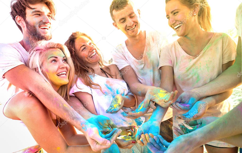 Young friends having fun at beach party on holi colors festival - Happy people playing together with genuine carefree mood at summer event - Youth friendship concept with multi colored sunshine filter