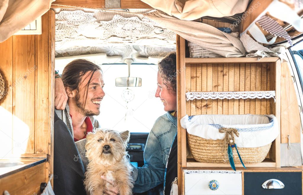 Indie couple with little dog traveling together on oldtimer mini van transport - Travel lifestyle concept with hipster people on minivan adventure trip having fun in relax moment - Warm retro filter