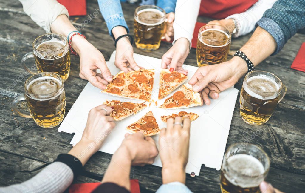 Millenial friends group drinking beer and sharing pizza slices at bar restaurant - Friendship concept with young people having fun together eating snack at risto pub pizzeria - Vintage contrast filter