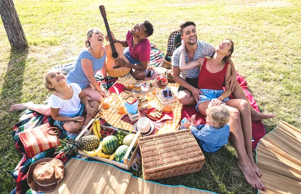 Blick von oben auf glückliche Familien, die mit Kindern bei Picknick-Grillparty Spaß haben - multiethnisches Liebeskonzept mit gemischten Rassenvölkern, die mit Kindern im öffentlichen Park spielen - warmer Retro-Vintage-Filter — Stockfoto