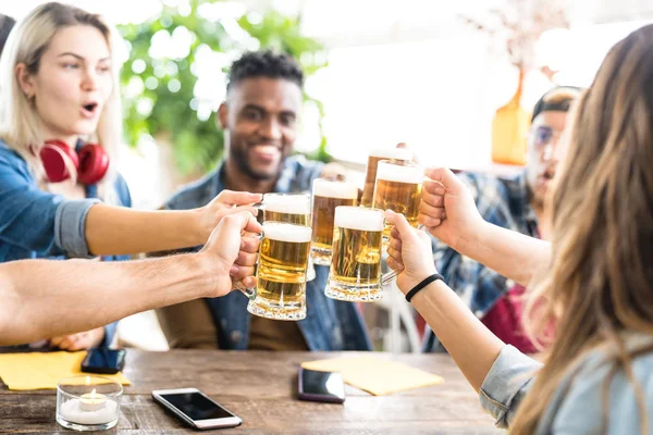Felices amigos multirraciales bebiendo y brindando por la cerveza en el bar de la cervecería - Concepto de amistad con los jóvenes divirtiéndose juntos en el restaurante cool pub - Enfoque en vasos de media pinta - Filtro brillante —  Fotos de Stock