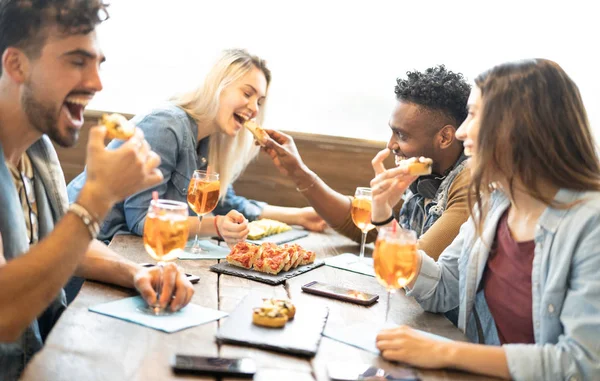 Amigos comiendo y bebiendo spritz en el restaurante bar de cócteles de moda - Concepto de amistad con los jóvenes divirtiéndose junto con bebidas y comida en la hora feliz en el pub - Centrarse en rebanadas de pizza —  Fotos de Stock