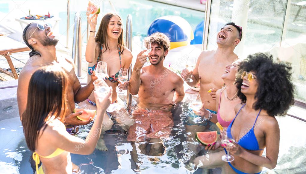 Side view of happy friends group drinking white wine champagne at swimming pool party - Luxury vacation concept with young guys and girls having fun in summer day at hotel resort - Warm bright filter