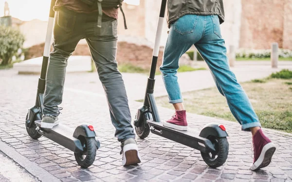 Close up of people couple using electric scooter in city park - Millenial students riding new modern ecological mean of transport - Green eco energy concept with zero emission - Warm sunshine filter — Stock Photo, Image